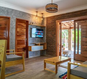 Ein Zimmer mit Fernseher, Holzmöbeln und Blick ins Freie.