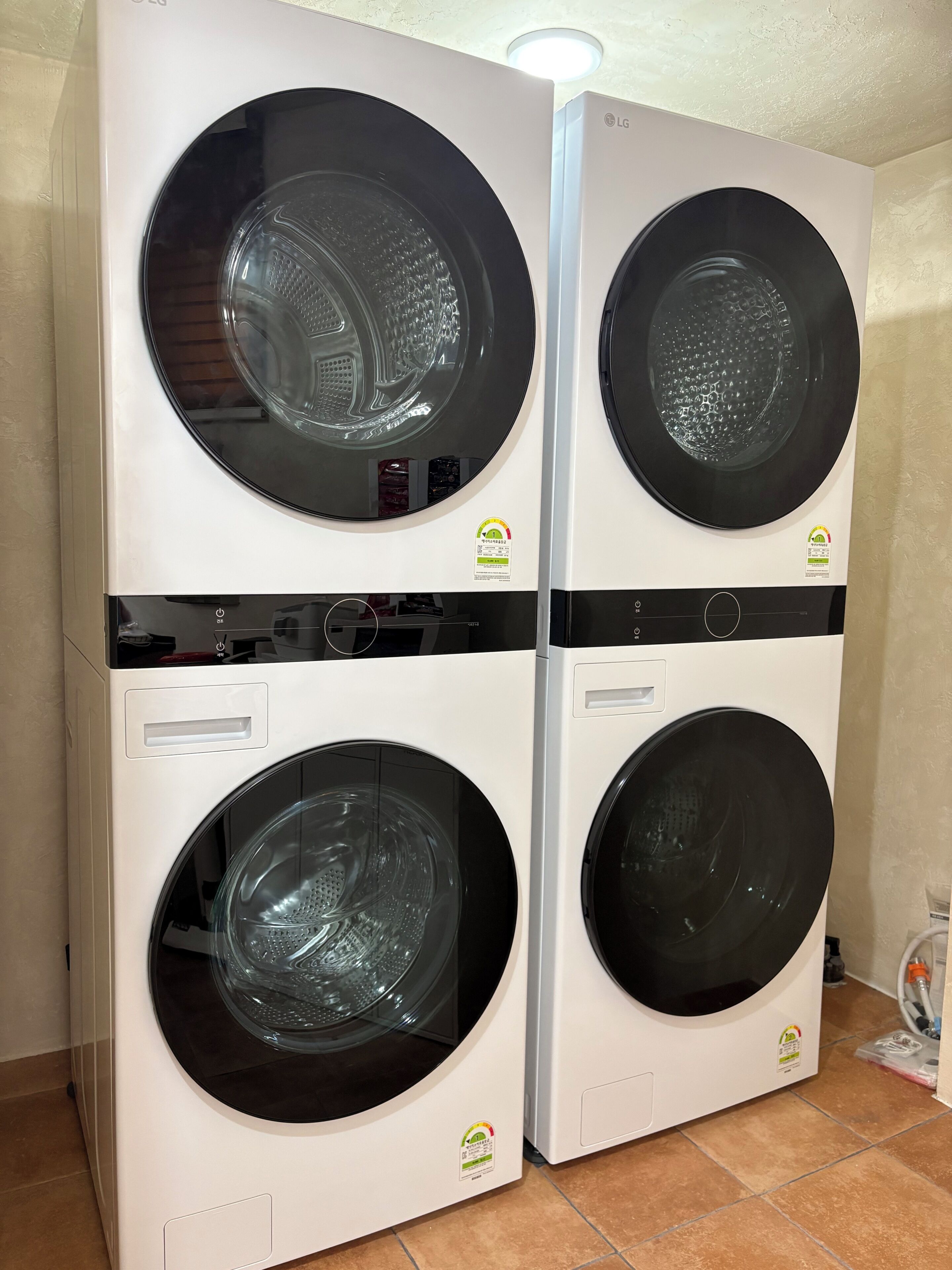 A double wall-mounted washing machine unit with a control panel and a power cord.