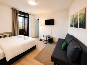 Une chambre d’hôtel avec un lit, un canapé, une télévision et un tableau au mur.