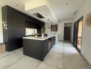 A modern kitchen with a central island, dark cabinetry, and a large window. - Luxury villa in the hills above Nîmes (Nîmes)