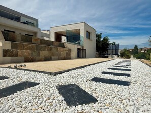 A modern building with a pebble pathway leading to a glass entrance.