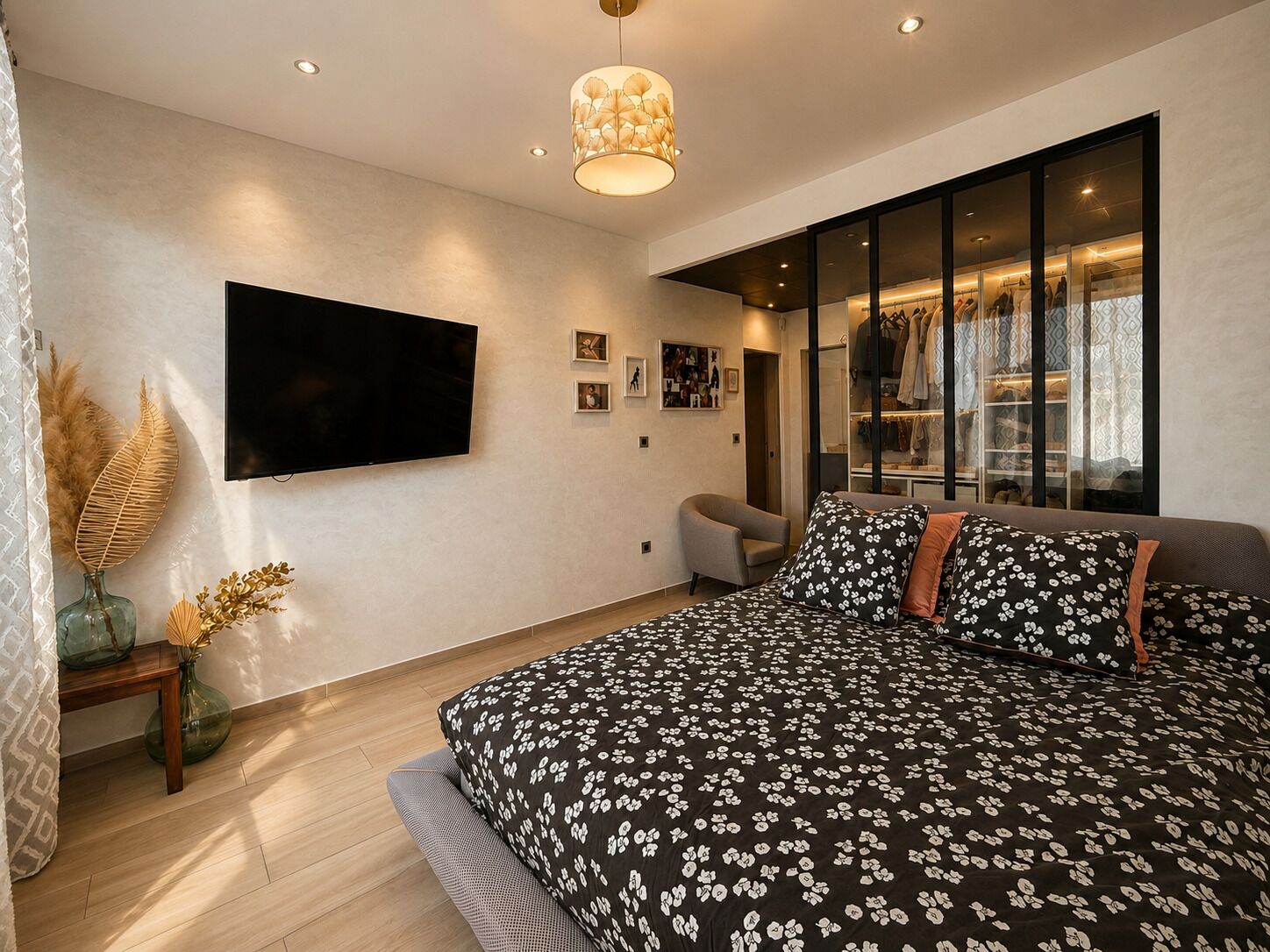 A modern bedroom with a large bed, a flat-screen TV, a wardrobe, and a large window.