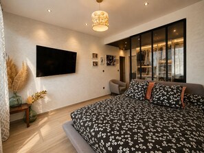 Une chambre moderne avec un grand lit, un téléviseur à écran plat, une armoire et une grande fenêtre.
