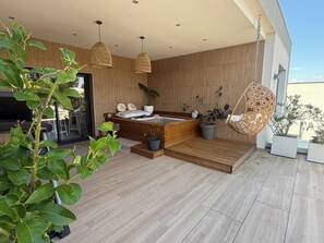 A modern outdoor living area with a wooden bench, a hot tub, and hanging wicker chairs. - Luxury villa in the hills above Nîmes (Nîmes)