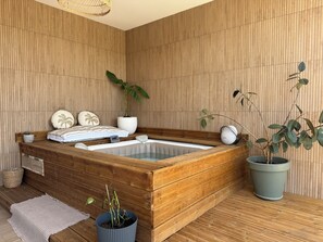 A wooden spa tub with a large potted plant, a small table with a plant, and a woven basket. - Luxury villa in the hills above Nîmes (Nîmes)