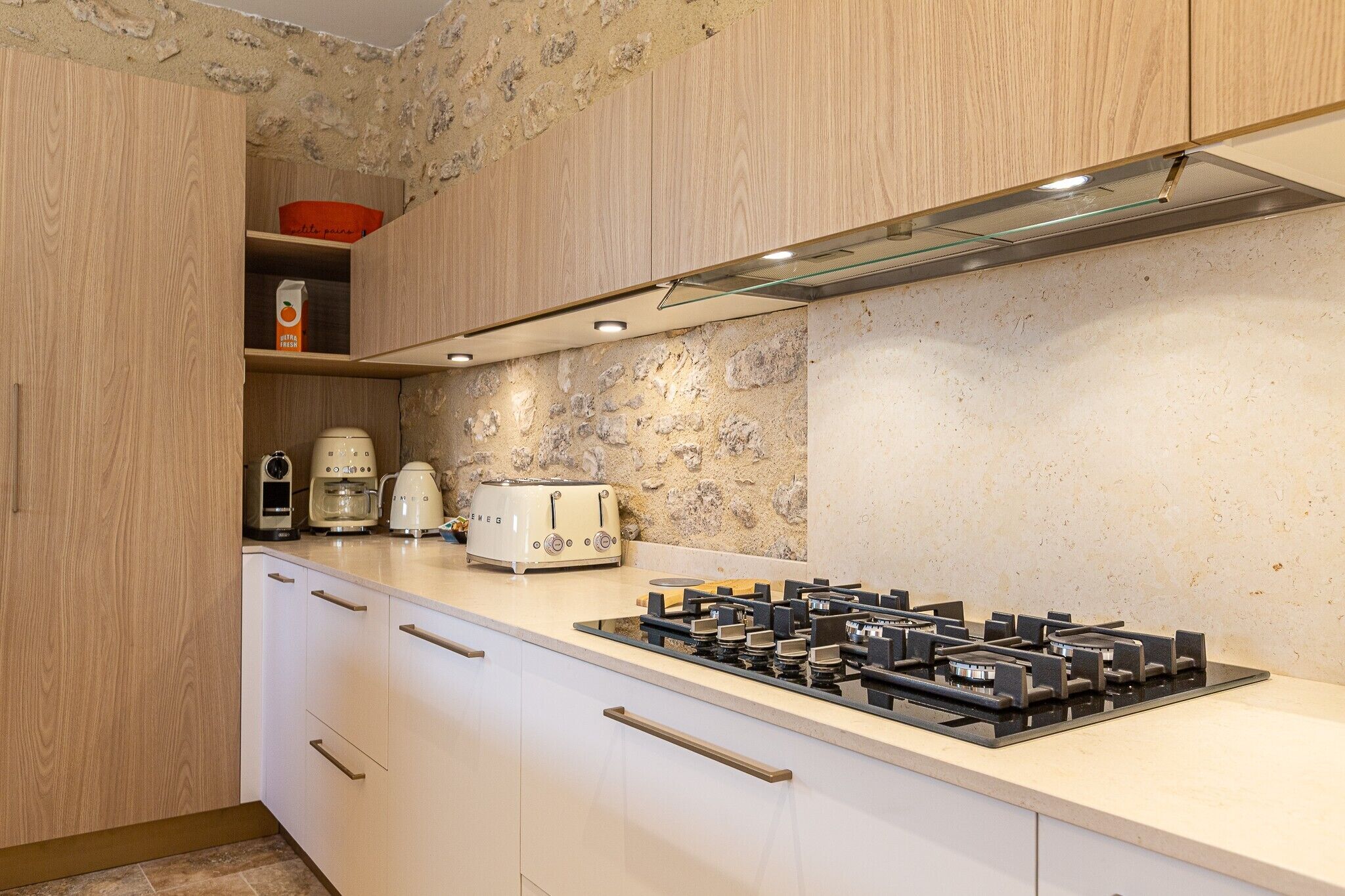 A kitchen with a gas stove, a coffee maker, and a toaster.