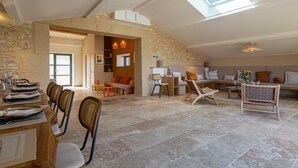 Ein großzügiger Loft mit hoher Decke, Steinwänden, einem Essbereich mit Stühlen und Tisch, gedecktem für eine Mahlzeit, einer Sitzecke mit Sofas und einem Couchtisch sowie einem Oberlicht.