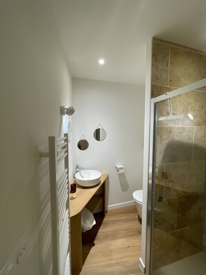 Ein modernes Badezimmer mit einem weißen Waschbecken, Spiegel und Dusche.