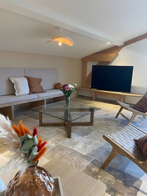 A modern living room with a glass coffee table, a sofa, a TV, and a decorative vase.