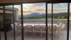 An outdoor dining area with a stone wall and a view of mountains.