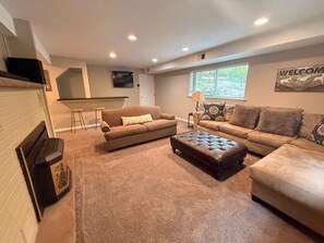 A living room with a fireplace, two couches, a coffee table, and a TV mounted on the wall.