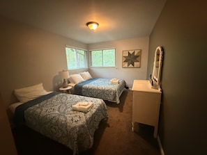 A bedroom with two beds, a nightstand, a dresser, and a star-shaped wall decoration.