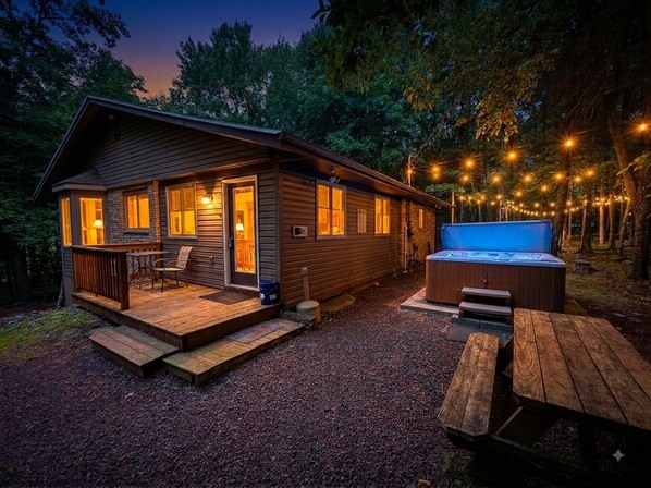 Una cabaña con terraza, jacuzzi y mobiliario de exterior.