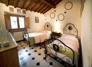 Un dormitorio con dos camas, techo de madera, una ventana y un radiador.