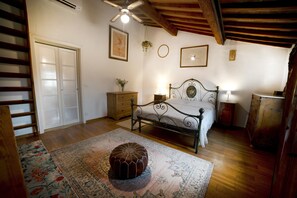 A bedroom with a bed, a wooden dresser, a nightstand, a hanging plant, and a ceiling fan. - Poetic Florence - Spacious Central Home: 3-BR, 2-Bath, Lift, View & Parking (Firenze)