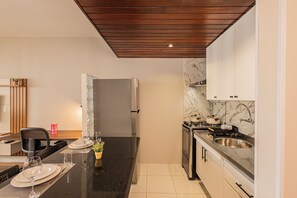 A modern kitchen with a marble backsplash, stainless steel appliances, and a wooden ceiling. - LTL - L'Etoile Residence by Anora Spaces (Barueri)