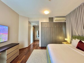 Ein Hotelzimmer mit einem Bett, einem an der Wand befestigten Fernseher, einem Kleiderschrank und einer Klimaanlage.