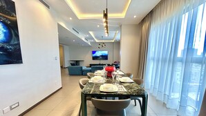 Un comedor moderno con una mesa de mármol, sillas y un televisor al fondo.