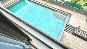 Ein Pool auf dem Dach mit freiem Blick zum Himmel und einer vorbeigehenden Person.