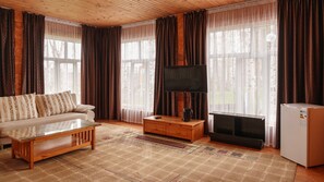 Uma sala de estar acolhedora com sofá, mesa de centro, televisão, lareira e frigorífico.
