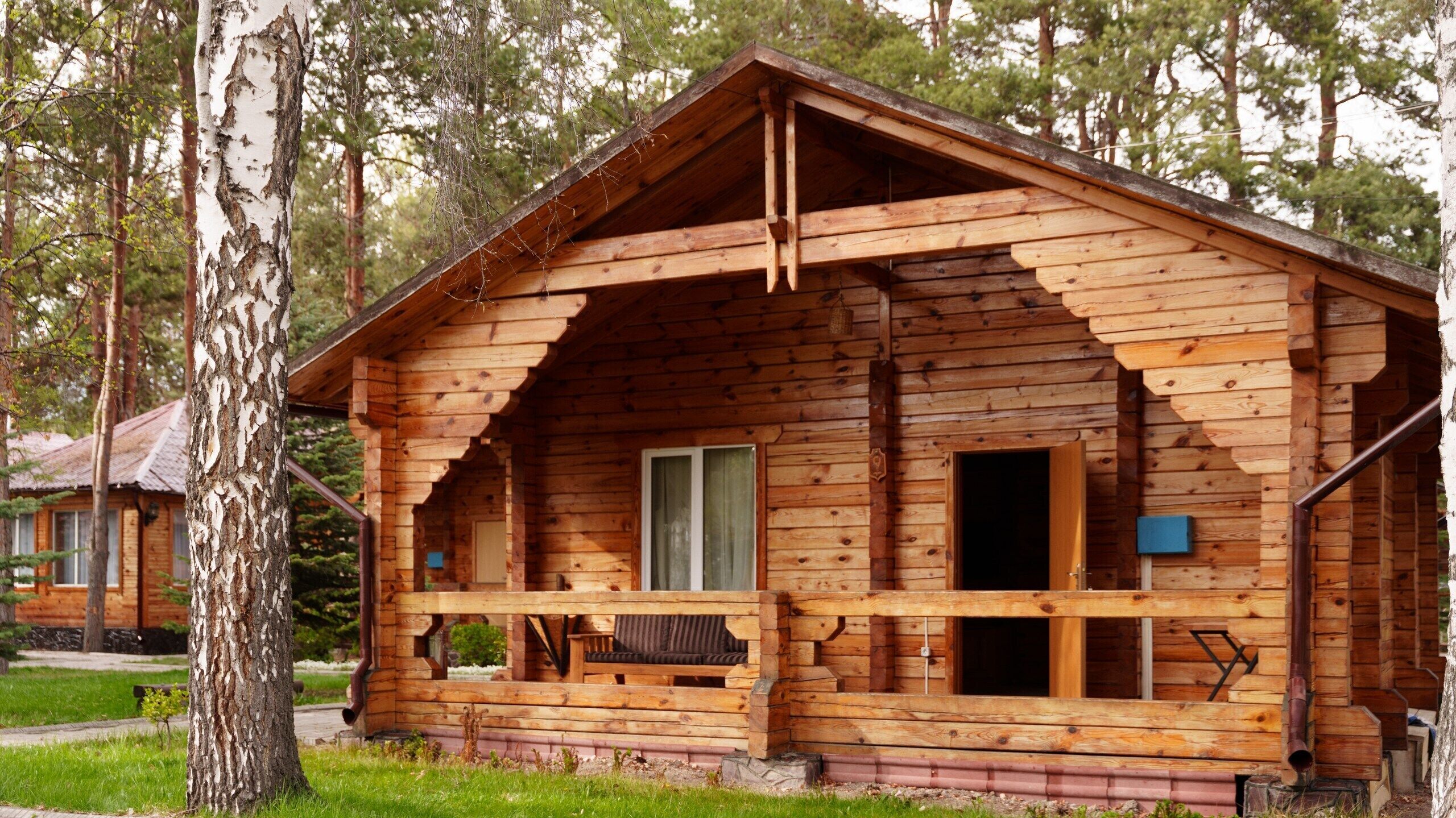 A wooden cabin with a porch, a window, and a door.