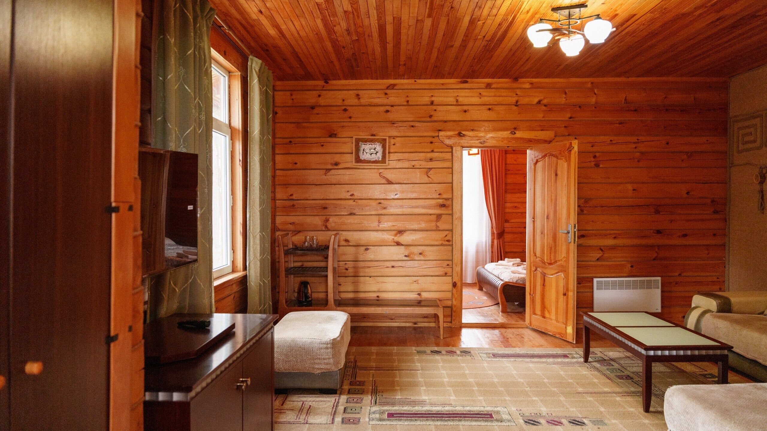 Interior acogedor de una cabaña con piso de madera, una cama, una mesa y un banco.