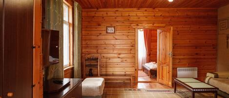 Interior acogedor de una cabaña con piso de madera, una cama, una mesa y un banco.