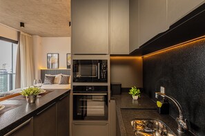 A modern kitchen with a built-in oven, microwave, and a sleek black backsplash. - VNM - VN Vila Olimpia by Anora Spaces (São Paulo)