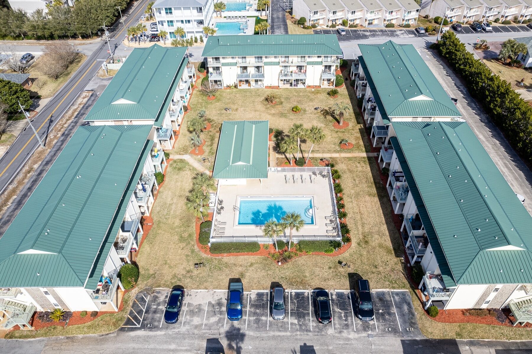 Vista aerea di un hotel con diversi edifici, una piscina centrale e un parcheggio.