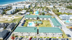 Un hotel su più piani con piscina, parcheggio e vista sulla spiaggia.