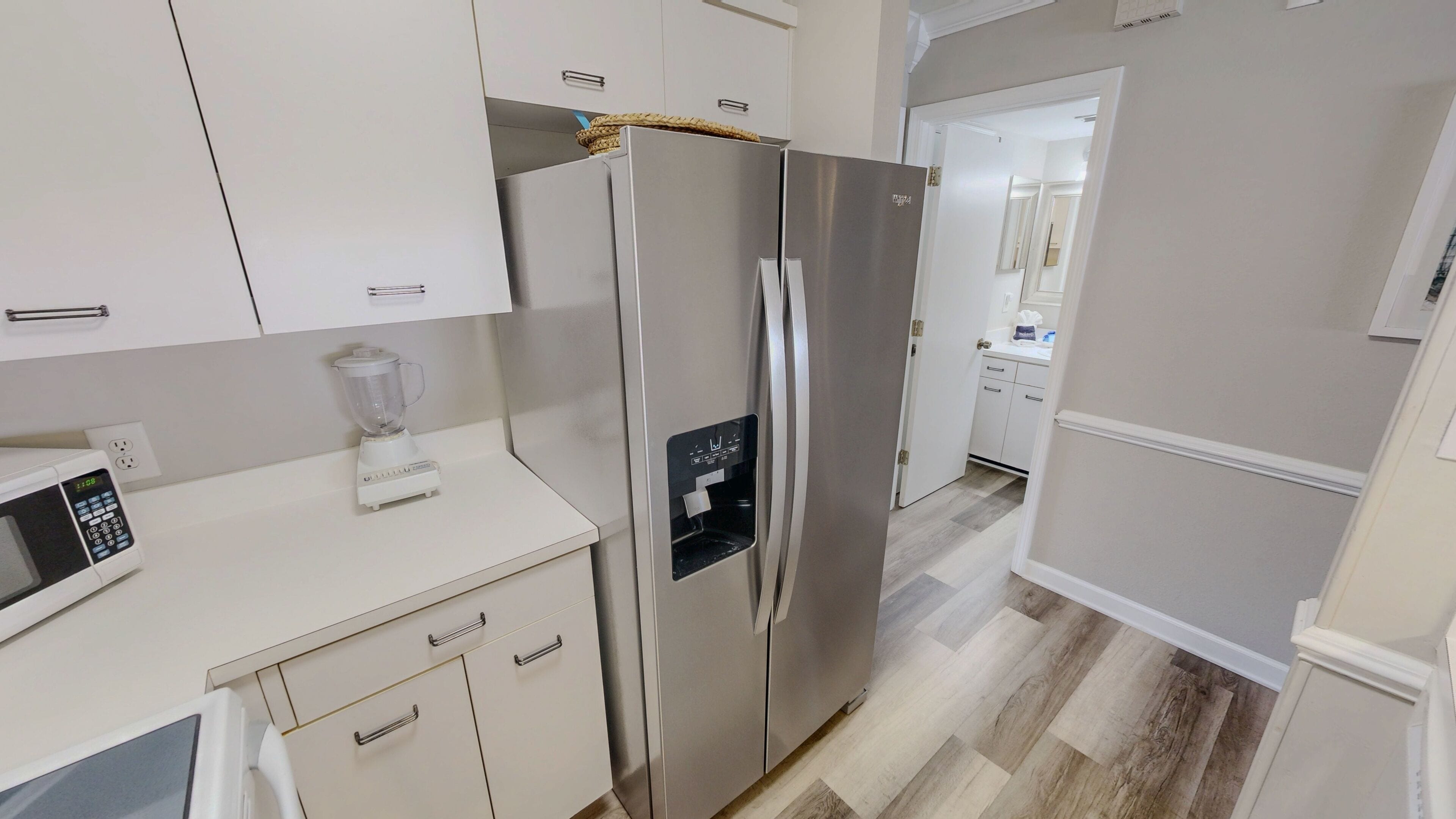 A kitchen with a stainless steel refrigerator, a microwave, and a blender on the counter.