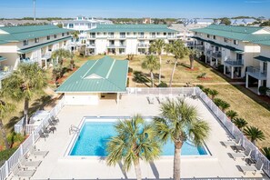 A pool area with lounge chairs and palm trees, surrounded by multi-story buildings with green roofs. - Sandprints B1 1 Bedroom Condo (Miramar Beach)