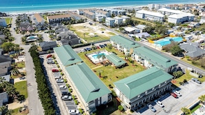 Vista aerea di un hotel costiero con diversi edifici, una piscina e una spiaggia sullo sfondo.