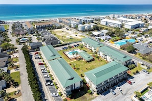 Vista aérea de un hotel costero con varias construcciones, una piscina y una playa al fondo.