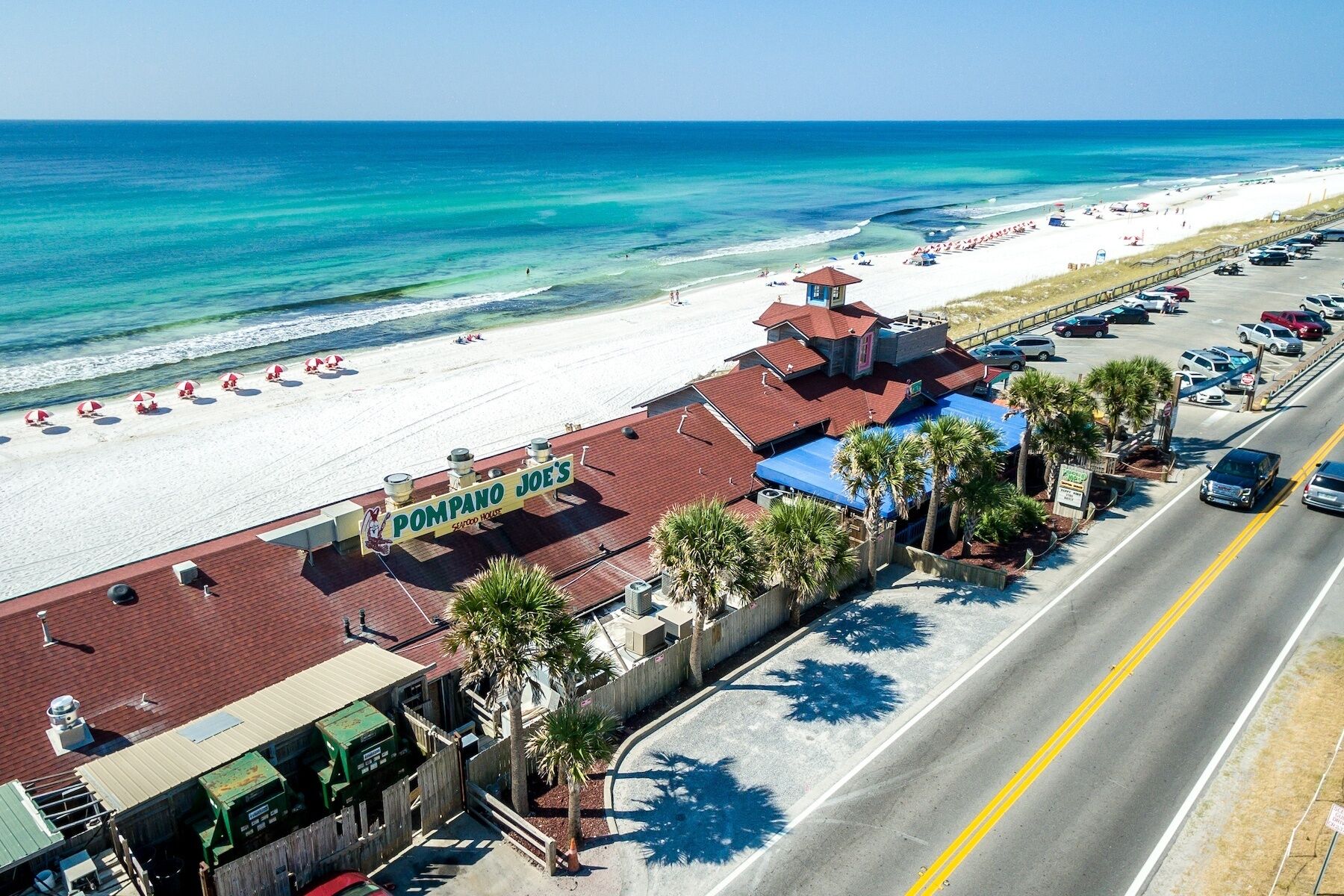 A beachfront property with a restaurant named 'Pompano Joe's Seafood House,' a parking lot, and a road adjacent to the beach.