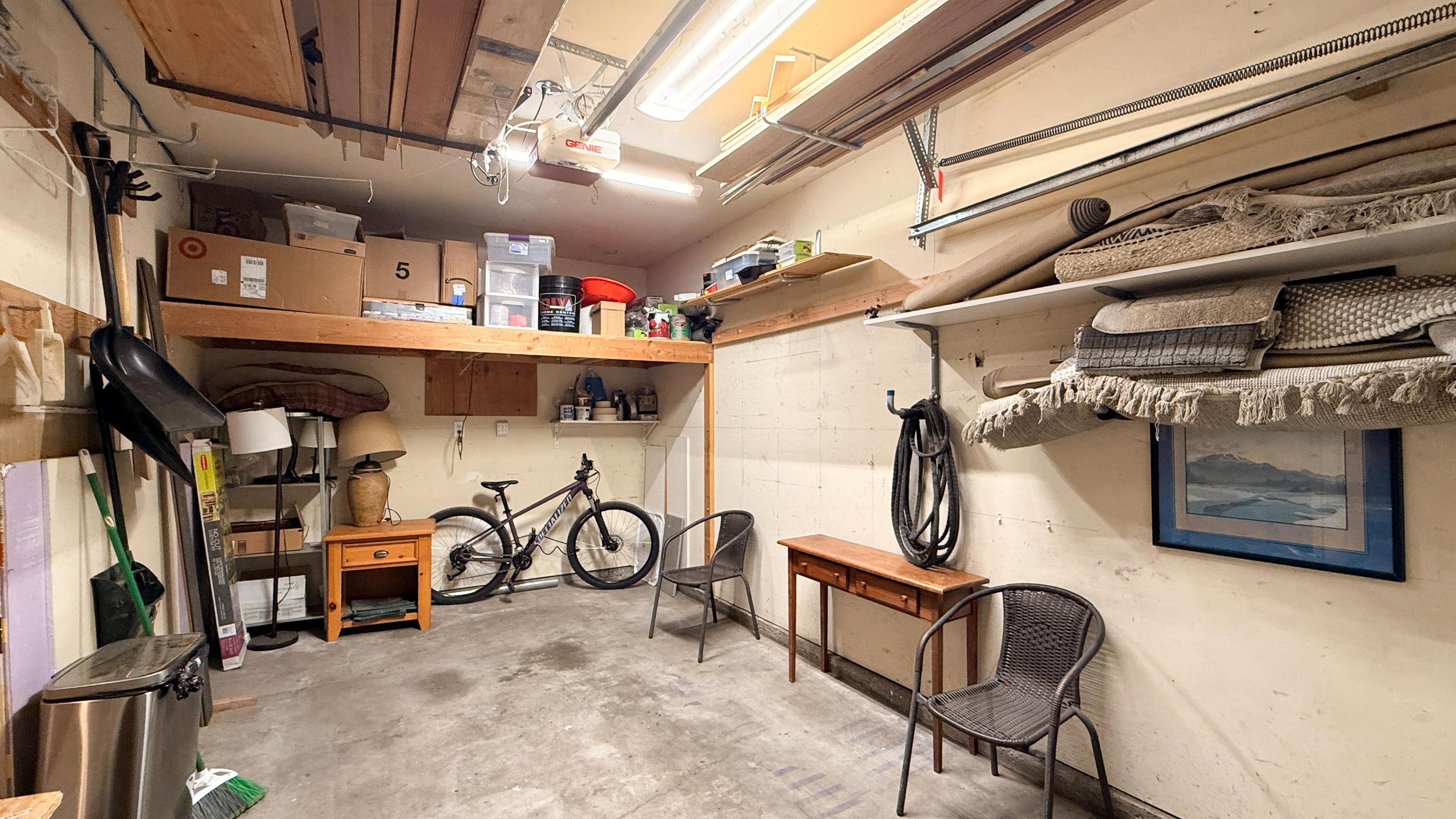 A cluttered garage with bicycles, shelves, and various items.