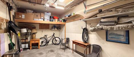 A cluttered garage with bicycles, shelves, and various items.