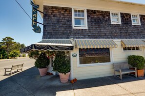 A building with a sign reading 'Pacific Way Cafe,' a bench, and potted plants. - Beachcomber's Retreat *Beach*Golf*Pets (Gearhart)