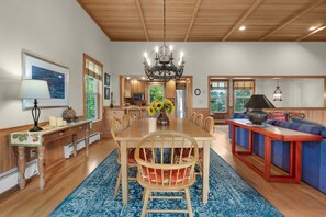 A spacious dining area with a wooden table, chairs, and a chandelier. - Beachcomber's Retreat *Beach*Golf*Pets (Gearhart)