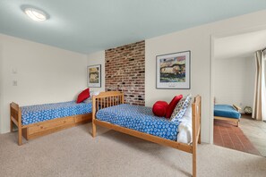 Ein Schlafzimmer mit zwei Holzbetten, einer Ziegelwand und einem gerahmten Bild an der Wand.