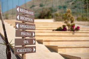 A directional sign with arrows pointing to various amenities including a restaurant, reception, spa, and pool.