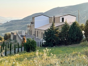 Un edificio moderno con fachada de piedra, un balcón y vistas del paisaje circundante.