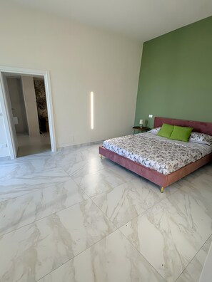 Um quarto com uma cama, parede verde e chão de mármore.