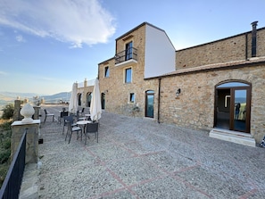 Un edificio de piedra con terraza, balcón y vistas al campo.