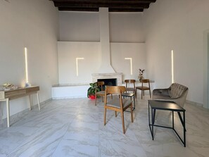 Uma sala de estar ampla com lareira, uma mesa de centro de madeira, um sofá e uma mesa de jantar.