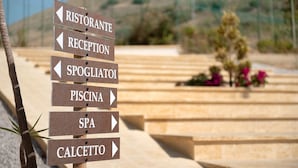 Placa indicativa com setas apontando para diversos serviços, como restaurante, recepção, spa e piscina.