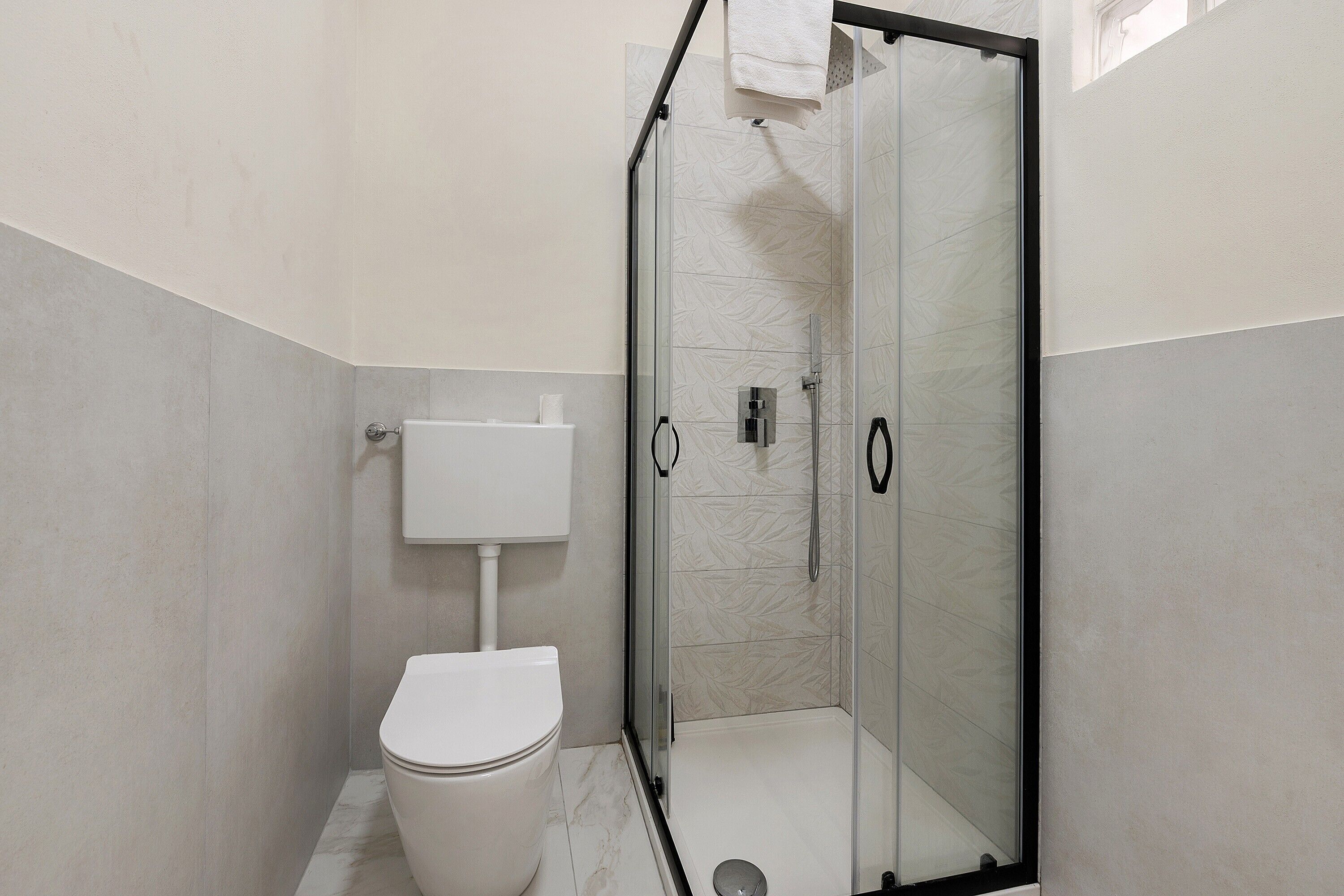 Ein modernes Badezimmer mit Toilette, einer gläsernen Dusche und einem weißen Waschbecken.