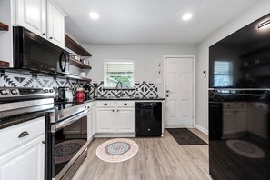 A modern kitchen with white cabinets, a black stove, and a dishwasher. - House with Security Gate - 7 min from downtown Houston (Houston)