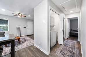 Una habitación con ventilador de techo, una mesa de comedor, un taburete de madera y un tapete estampado.