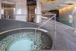 Ein moderner Innenpool mit Glasverkleidung, einer Whirlwanne und einem Spa-Bereich.